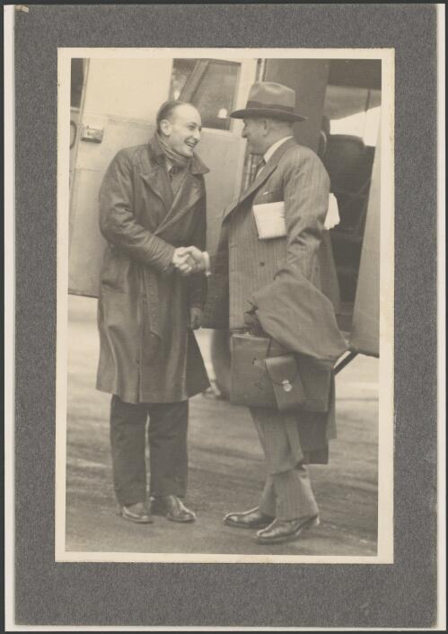 Pilot James Weir shaking hands with Harry Hinckson of Shell Australia in front of an open aircraft cabin door, ca. 1930s [picture]