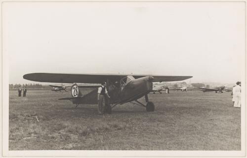 Mr H. Hughes standing beside Desoutter Mk.II aeroplane (VH-UPR) on an airfield for the South Australian Centenary Air Race, 1936 [picture]