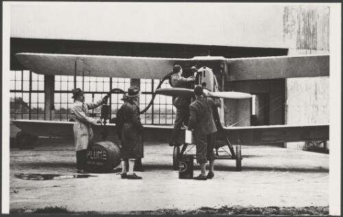 Charles Kingsford-Smith, in centre, watching the refuelling of his Avro Avian biplane, G-ABCF, Southern Cross Junior, outside a hangar, ca. 1930 [picture]
