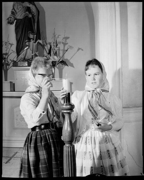 Two Home of the Good Shepherd girls' home girls lighting a candle during mass in the chapel, Ashfield, 8 October, 1963 [picture] / John Mulligan