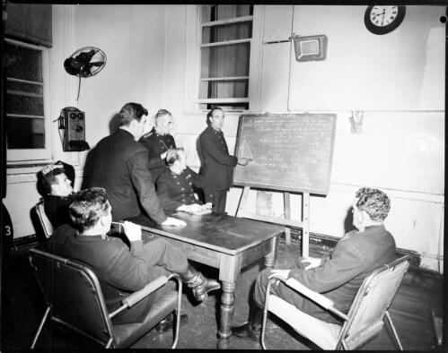 An instructor using a blackboard to demonstrate the formula for putting a ladder up to firemen during training at a New South Wales Fire Brigade headquarters, Sydney, 25 June, 1962 [picture] / John Mulligan