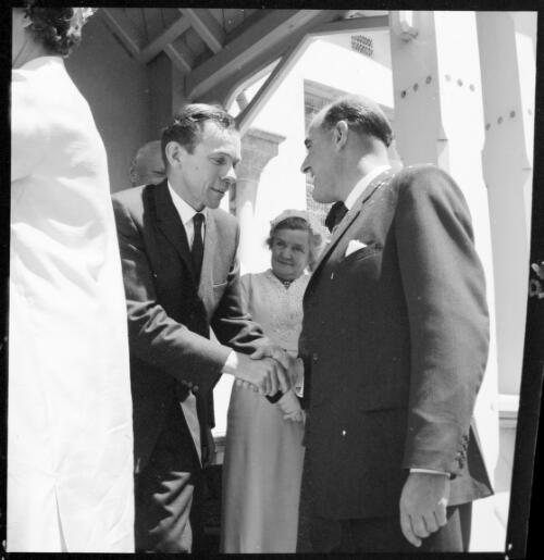 The groom shaking hands with an unidentified man on the steps of the portico of the Christ Church Anglican church during the Val Westmacott wedding, Bong Bong, Southern Highlands, New South Wales, 2 November, 1962 [picture] / John Mulligan