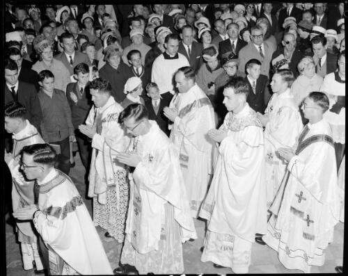 Newly ordained priests walking past parishioners after their ordination during first mass at St. Mary's Cathedral, Sydney, 19 July, 1963 [picture] / John Mulligan