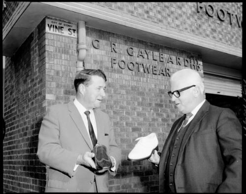 Two unidentified men hold newly made shoes outside the G.R. Gayleard Footwear factory, Vine street, Sydney, 17 July, 1968 [1] [picture] / John Mulligan