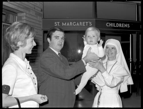 Mr and Mrs Barry Foley handing their child, Benjamin, to Sister Jenna at a new childminding centre, St. Margaret's Childrens Hospital, Sydney, 16 October 1970 [1] [picture] / John Mulligan
