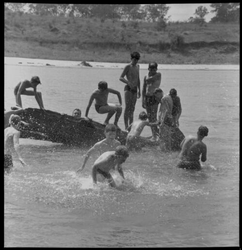 Group of boys playing with log in river at an Adventure Training Camp, Richmond, New South Wales, 19 January 1964 [4] [picture] / John Mulligan