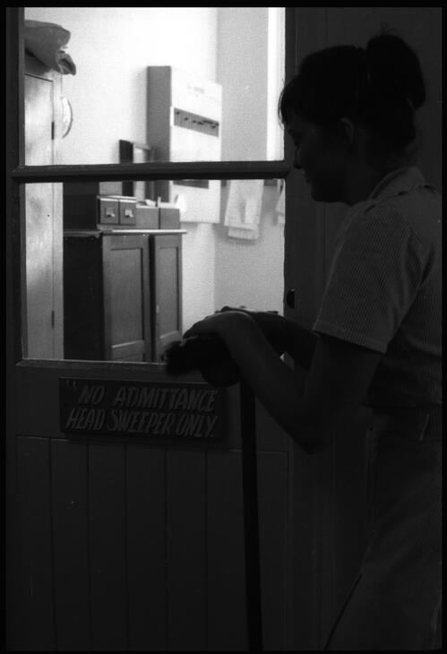 Prisoner leaning on broom outside door with "No Admittance Head Sweeper Only" sign at the State Reformatory for Women, Long Bay, Sydney [2] [picture] / John Mulligan
