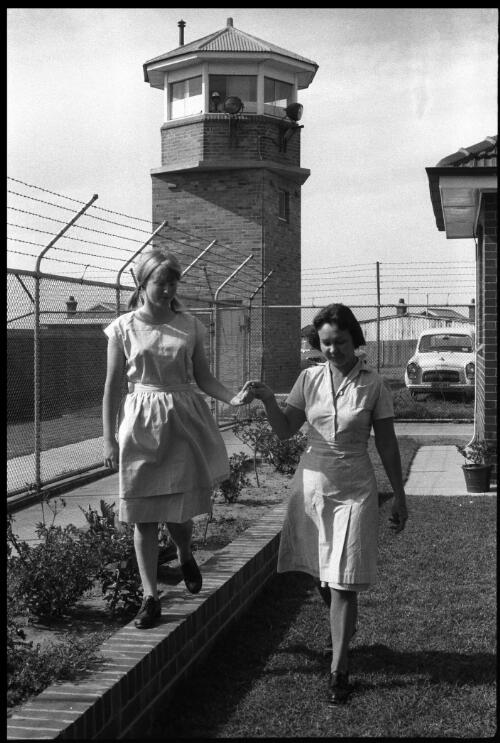 Two prisoners walking in garden under tower, State Reformatory for Women, Long Bay, Sydney [1] [picture] / John Mulligan