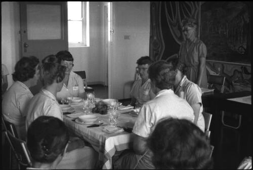Group of prisoners seated at formal dining table with unidentified woman standing behind desk, State Reformatory for Women, Long Bay, Sydney [1] [picture] / John Mulligan