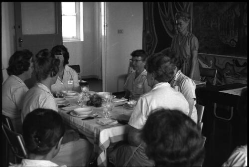 Group of prisoners seated at formal dining table with unidentified woman standing behind desk, State Reformatory for Women, Long Bay, Sydney [2] [picture] / John Mulligan