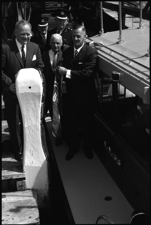 Unidentified man removing flag from new police launch Nemesis which will be used to combat drug trafficking, Sydney Harbour, 6 June 1966 [2] [picture] / John Mulligan