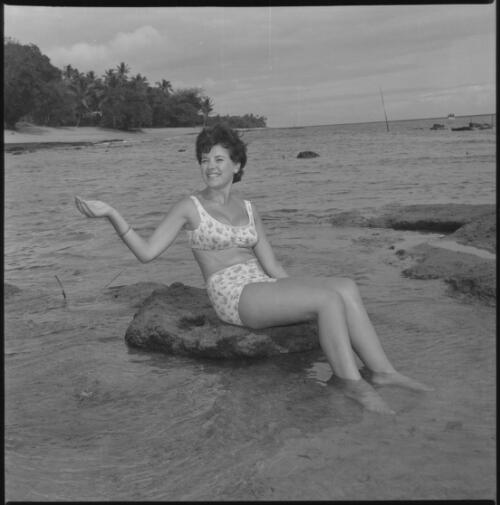 Miss Maglia wearing a bikini and sitting on a rock in the sea at Suva, Fiji, 22 February 1966 [1] [picture] / John Mulligan