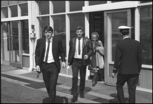 Con Cluskey of the musical group "The Bachelors", followed by an unidentified man and woman leaving a building at Mascot Airport, Sydney, 27 September 1965 [picture] / John Mulligan