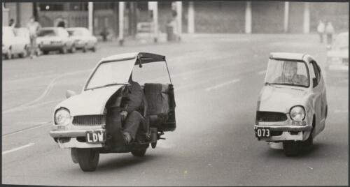 Photograph from the film Malcolm, showing the car split in two with both halves being driven down a street, Melbourne, 1986 [picture] / John Ogden