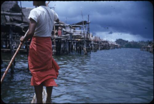 Tupesleia village, a man navigating amongst the houses Port Moresby, Papua New Guinea, 1953 [picture] / Terence and Margaret Spencer