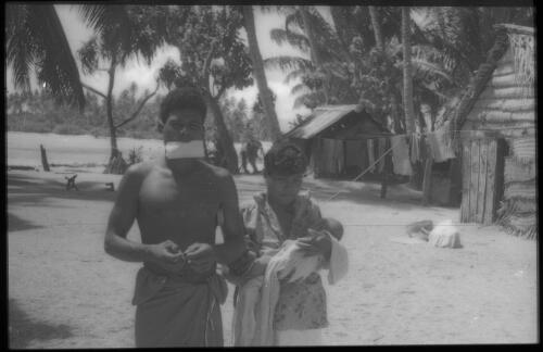Man and woman holding a baby with house in background Carteret Islands, Papua New Guinea, 1960 [picture] / Terence and Margaret Spencer
