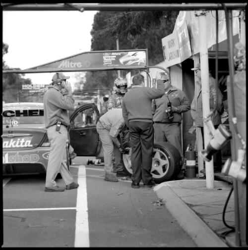 [Car race, car and driver in pits, tyres being checked and men in one group, one man with headphones to left of group, GMC 400 V8 Supercar Series 2000, Canberra, 9-11 June 2000] [picture] / Damian McDonald