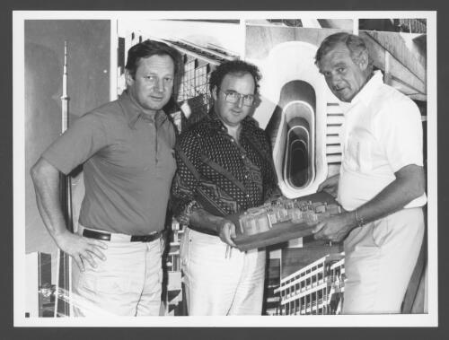 [Portrait of John Andrews examining a model of the proposed Intelsat building with his partners, Mr John Simpson, centre, and Mr Peter Courtney, 1980] [picture] / [Robert Maccoll]