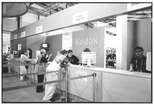 Main counter staff at the Kodak Image Centre assisting customers with film orders, collection and replacement, Outback Pavilion, Main Press Centre, [Sydney 2000 Olympics], Homebush Site, September 2000 [picture] / Brian Leonard