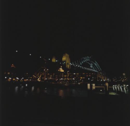[Night-time in the Sydney Harbour Rocks area, Campbells Cove, Sydney Harbour Bridge & sailing ships, Sydney, 17 August 2000] [transparency] / Loui Seselja