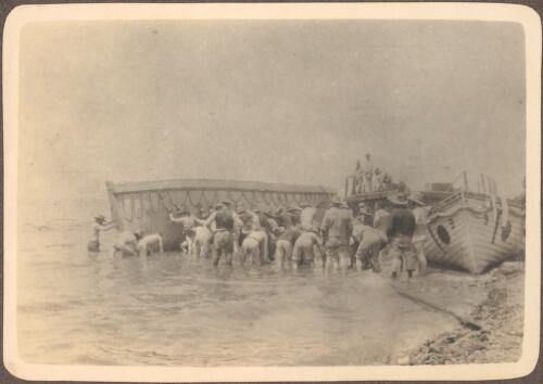 Hauling boats alongside, [at Anzac Beach where soldiers push a pinnace alongside another pinnace sitting on the water's edge, May 21, 1915] [picture] / J.P. Campbell