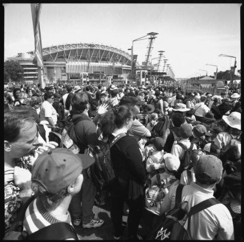 Crowd queuing to enter an unspecified event, Olympic Stadium in background, Sydney 2000 Paralympic Games, 23 October 2000 [picture] / Louis Seselja