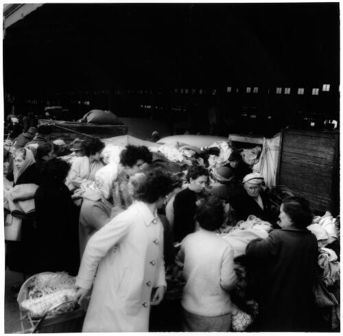 Spotting a bargain at the second-hand goods stalls, Queen Victoria Markets, Melbourne, 1956 [picture] / Jeff Carter