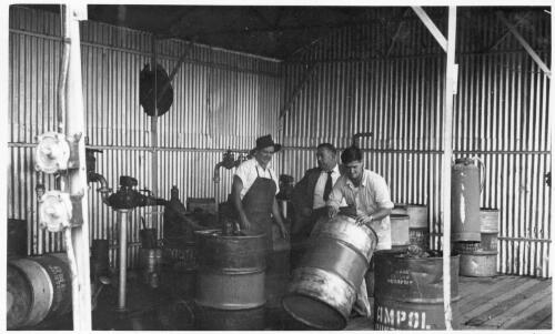 View of three unidentified employees moving drums on the drum platform, Cootamundra Depot, April, 1955 [picture]
