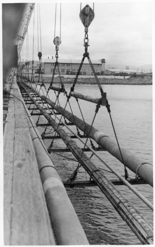 View of the an underwater pipeline on a series of small cranes at the no.6 jetty at the Port Kembla shipping terminal, 21 March, 1959 [picture]