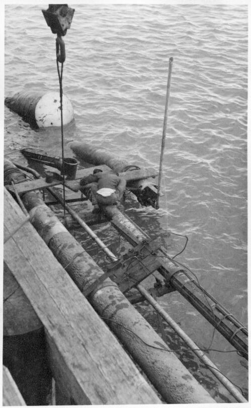 View of a pipeline construction worker making an over water connection in the vacuum and B.P. line of an underwater pipeline at the no.6 jetty prior at the Port Kembla shipping terminal, 27 May, 1959 [picture]