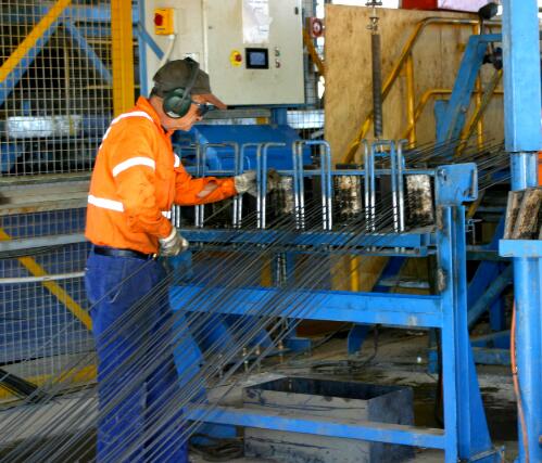 Tensioning wires for sleepers being loaded at Tenant [i.e. Tennant] Creek sleeper factory [picture] / June Orford