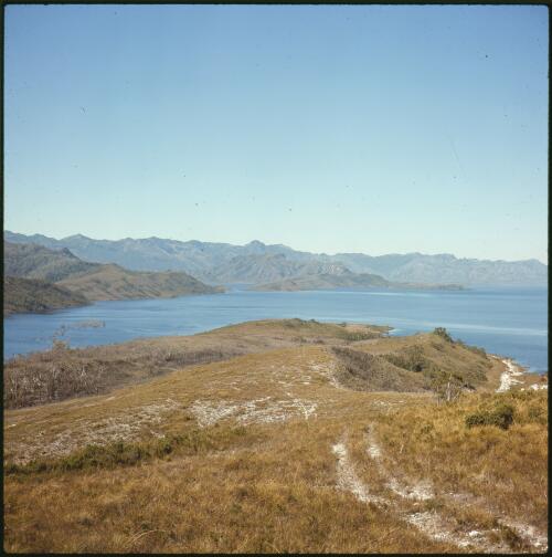 Lake Pedder partly filled, looking down grassy ridge with four wheel drive track, Tasmania, ca. 1973, 1 [transparency] / Russ Ashton