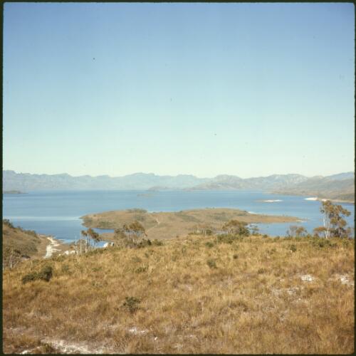 Lake Pedder partly filled, looking from grassy high land down to peninsula, Tasmania, ca. 1973 [transparency] / Russ Ashton