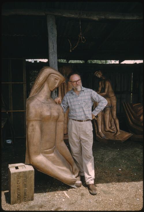 Portrait of Tom Bass standing next to his sculpture at his studio in Minto, New South Wales, ca. 1961 [transparency] / James Whitelock