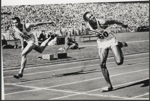 Right on the line at the finish of the 110 metres hurdle, the camera gives it to Lee Calhoun (right) of the United States from his teammate Jack Davis, Melbourne Cricket Ground, Olympic Games, Victoria 1956 [picture] / Bruce Howard