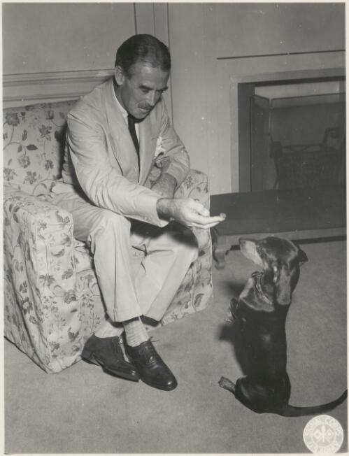 R.G. Casey seated playing with pet dog Mizr, Washington, United States ca. 1941 [picture]