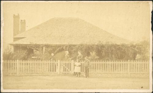 Women and children standing outside a brick house with two chimneys and picket fence, Hill End, New South Wales, ca. 1873 [picture] / Beaufoy Merlin