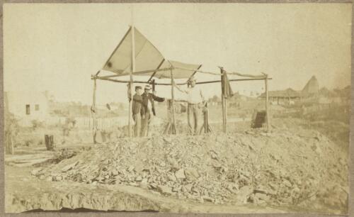 Three men, one in uniform, at mine head with pile of mullock and canvas awning, Scandinavian mine background right, Hill End, New South Wales, ca. 1872 [picture]