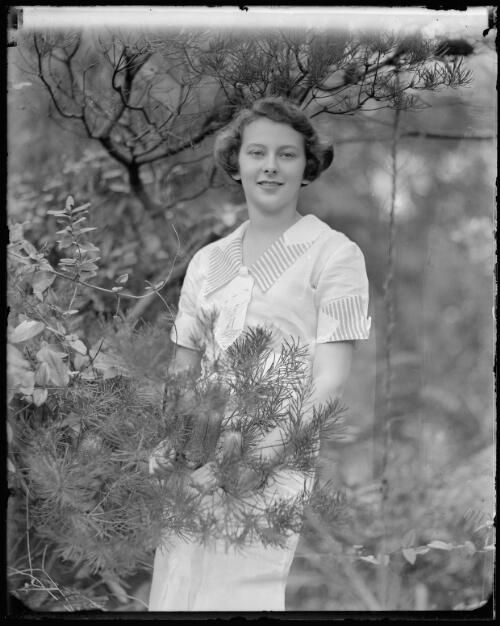 Lucille Dupain standing behind native bush, 1935 [picture] / Harold Cazneaux
