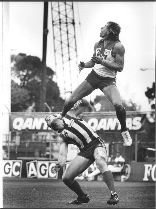 Sydney's Warwick Capper taking a spectacular mark over Mick Martin of the Kangaroos in a game at the MCG on Anzac Day 1991, 2 [picture] / Bruce Howard