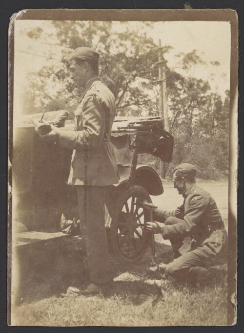 Horrie Miller (kneeling) and an unidentified man in Australian Flying Corps uniforms mend a car tyre, ca. 1918 [picture]
