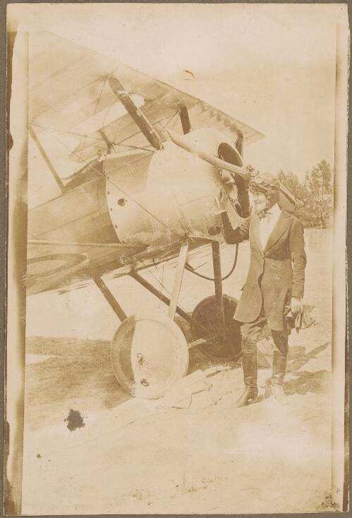 Woman wearing a flying cap and goggles stands next to Dove biplane K168, Glenelg, 1919 [picture]