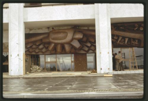 Installing the Tom Bass lintel sculpture over the main entrance to the National Library of Australia, Canberra, Australian Capital Territory, May 1969, 2 [transparency] / Kevin Goodridge