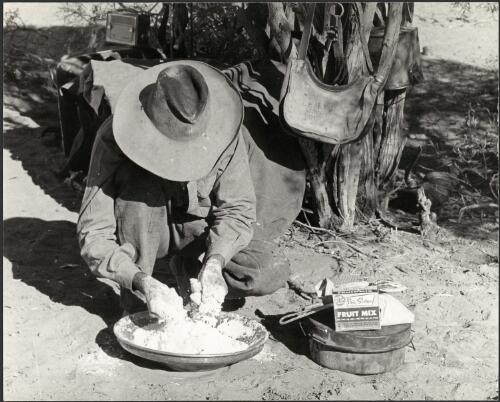 Drover and cook Azzi Fazulla mixes flour and raisins to make a Johnny Cake damper,  Starvation Lake, South Australia, 1963 [picture] / Jeff Carter