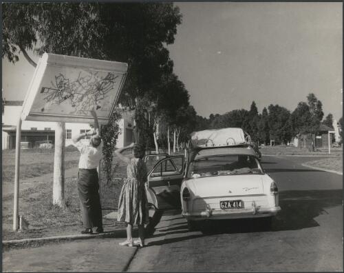 Victorian tourists look at a street map in north Canberra, 1959 [picture] / Jeff Carter