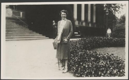 Molly Fink standing in the driveway in front of a grand building, ca. 1930 [picture]