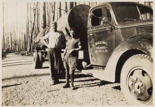 Two men standing next to a G. Higgins logging truck on the road not far from the mill, early 1940s? [picture]