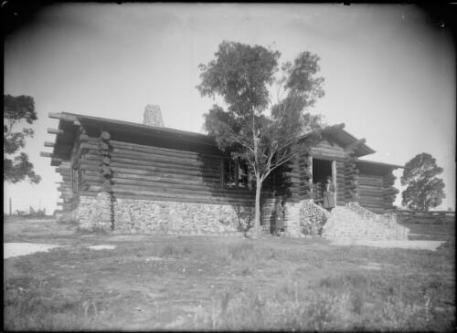 Girl Guides in uniform standing in front of a substantial log cabin with stone chimney, the Girl Guides hall, Eden, ca. 1936, [1] [picture]