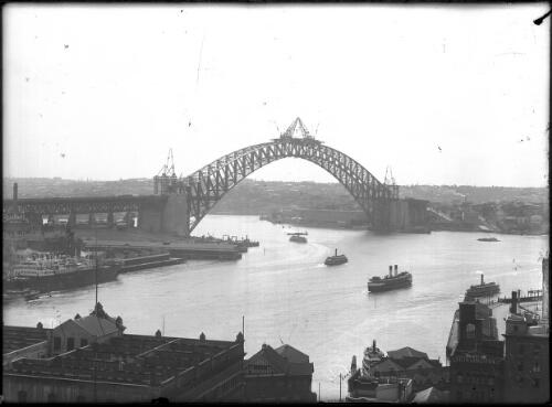 Sydney Harbour Bridge, meeting of the arch; ship at Circular Quay; ferries on harbour, 1930, [1] [picture]