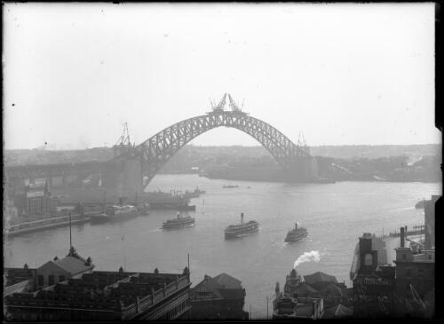 Sydney Harbour Bridge, meeting of the arch; ship at Circular Quay; ferries on harbour, 1930, [2] [picture]